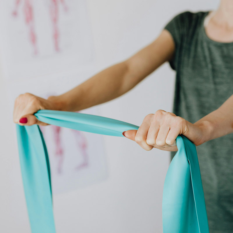 Eine Frau trainiert mit einem grünen Theraband