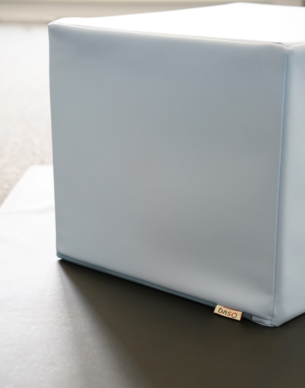 Ein hellblauer Lagerungswürfel liegt auf einer Therapieliege